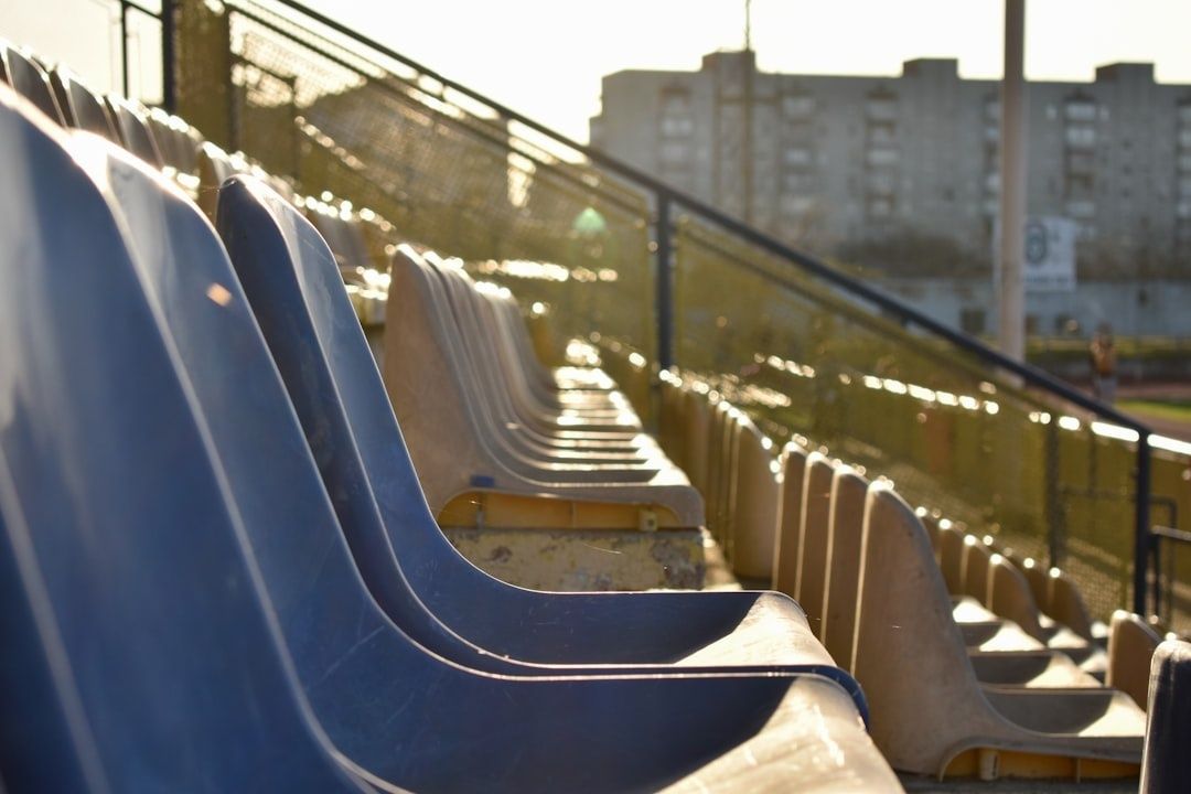 Leere blaue und beige Stadionsitze im warmen Abendlicht