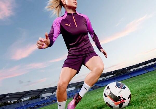 Fußballerin in Stollenschuhen auf dem Rasen eines Stadions