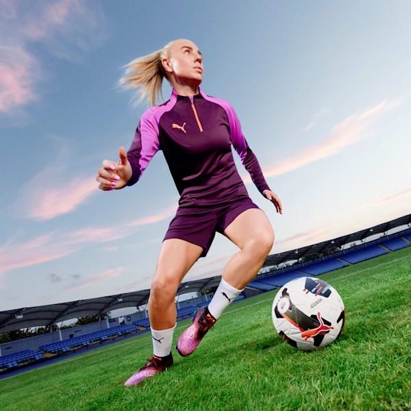 Fußballerin in Stollenschuhen auf dem Rasen eines Stadions