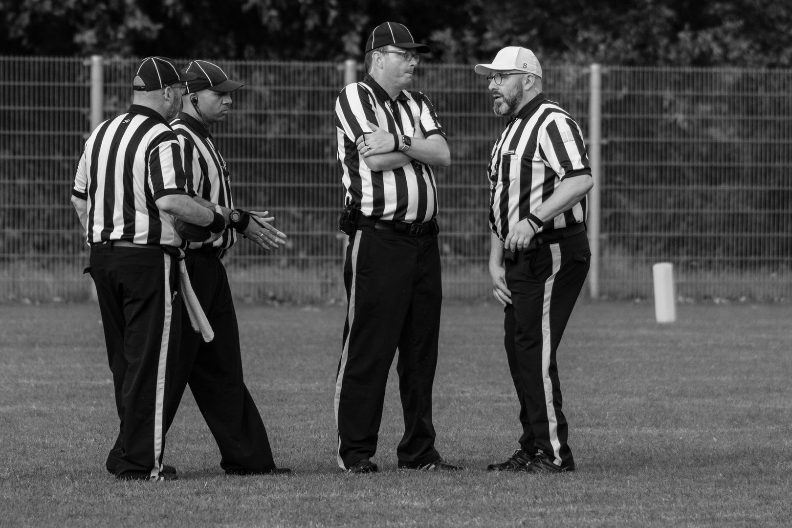 Vier Schiedsrichter besprechen sich auf einem Fußballplatz