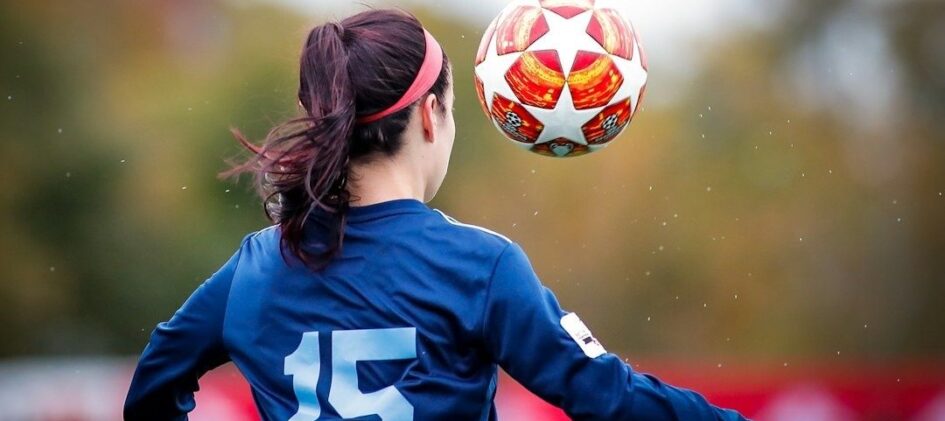 Fußballerin mit Rückennummer 15 fokussiert einen fliegenden Ball