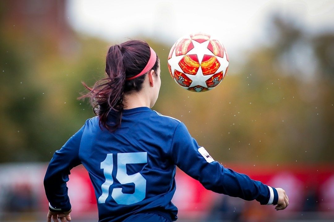 Fußballerin mit der Rückennummer 15 und Ball im Sprungmoment